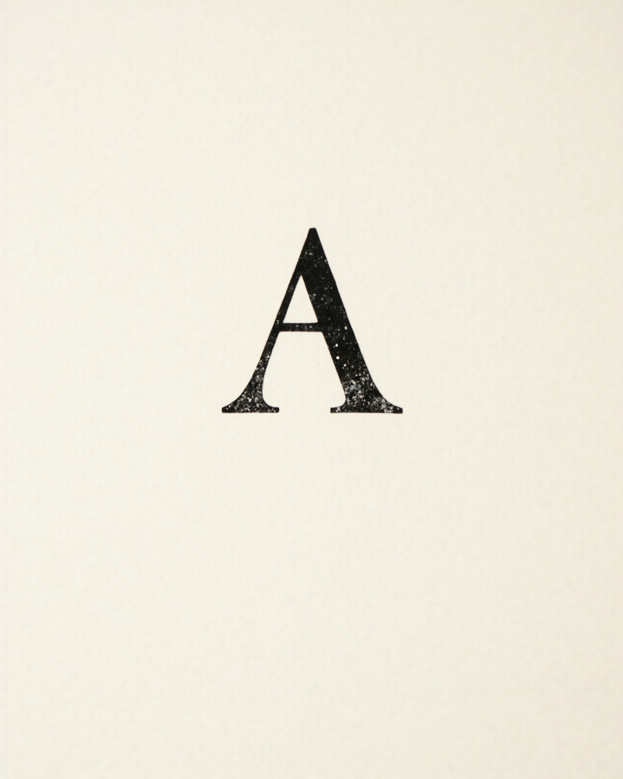 A single black serif capital A printed on cream paper